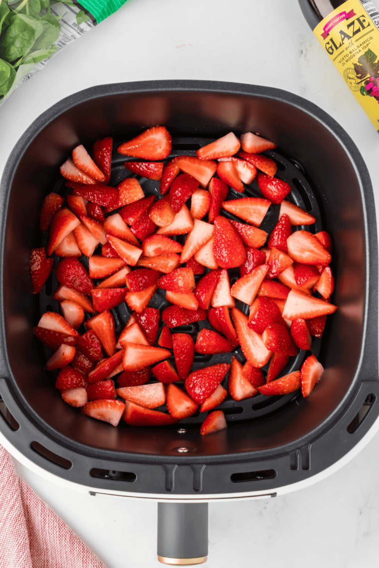 Strawberry candy drying in the air fryer, slices shrunken and chewy after low-temperature dehydrating