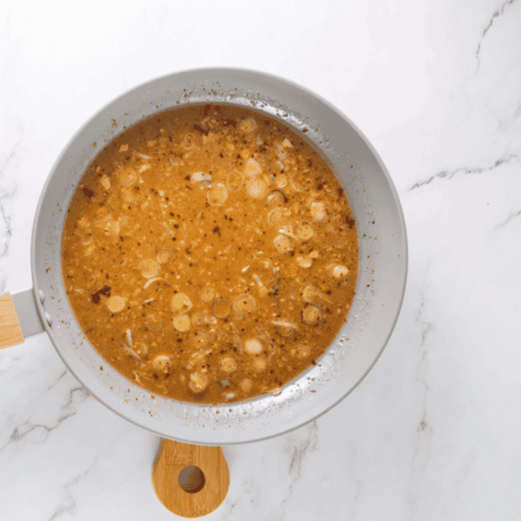 Mixing a golden honey-orange glaze in a bowl with garlic, ginger, soy sauce, and spices.