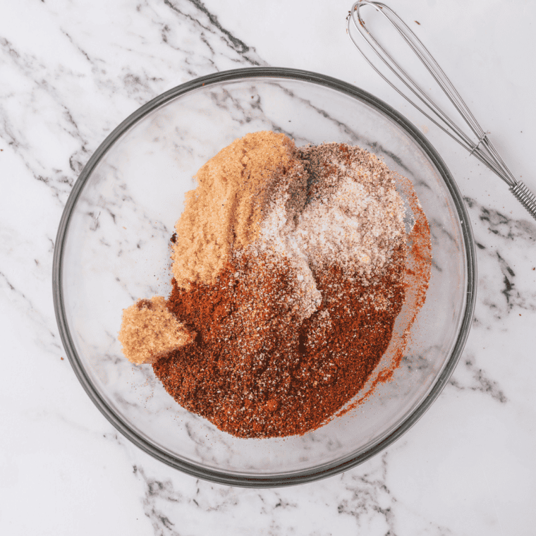 Fiesta seasoning spices measured into a white bowl before mixing