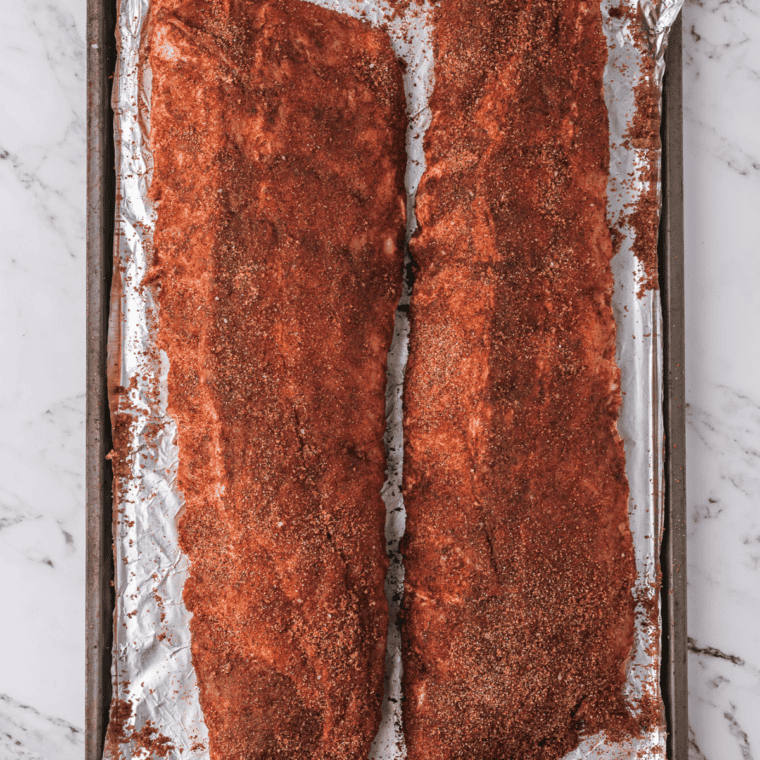 Raw ribs fully coated in homemade fiesta rub, ready to cook