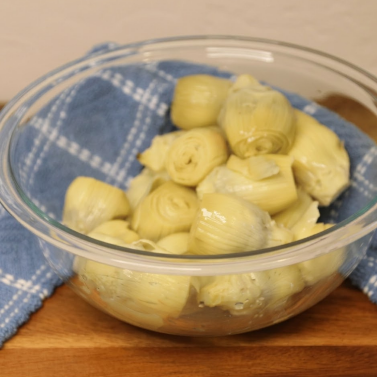 Draining canned artichoke hearts in a colander before air frying.