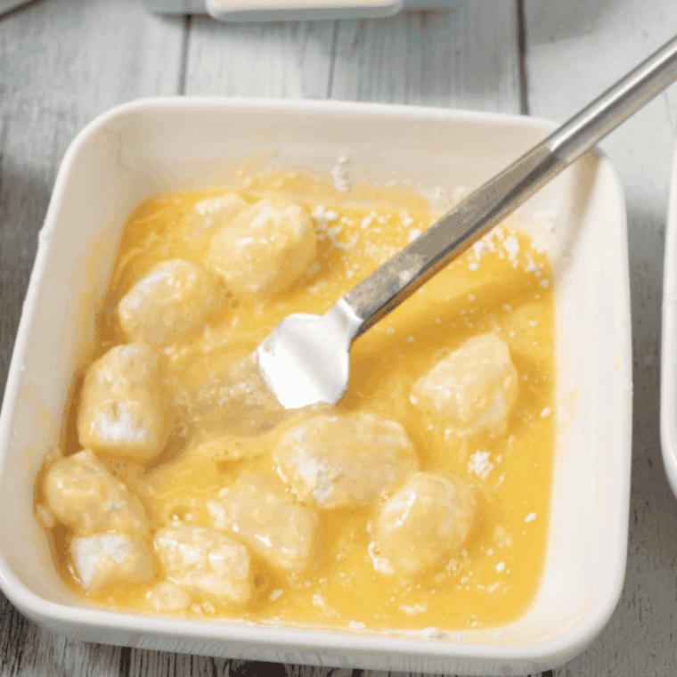 Three shallow dishes set up for breading station with seasoned flour, beaten egg, and crushed Ritz crackers with garlic powder and paprika