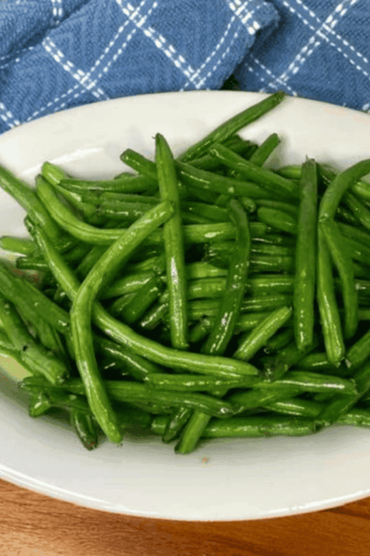 Air-fried green beans coated in garlic butter sauce, served crispy and golden in a bowl.
