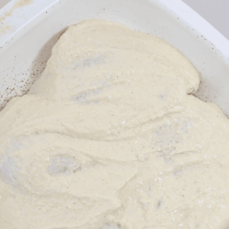 Coating chicken thighs in Caesar mixture and pork rind crumbs