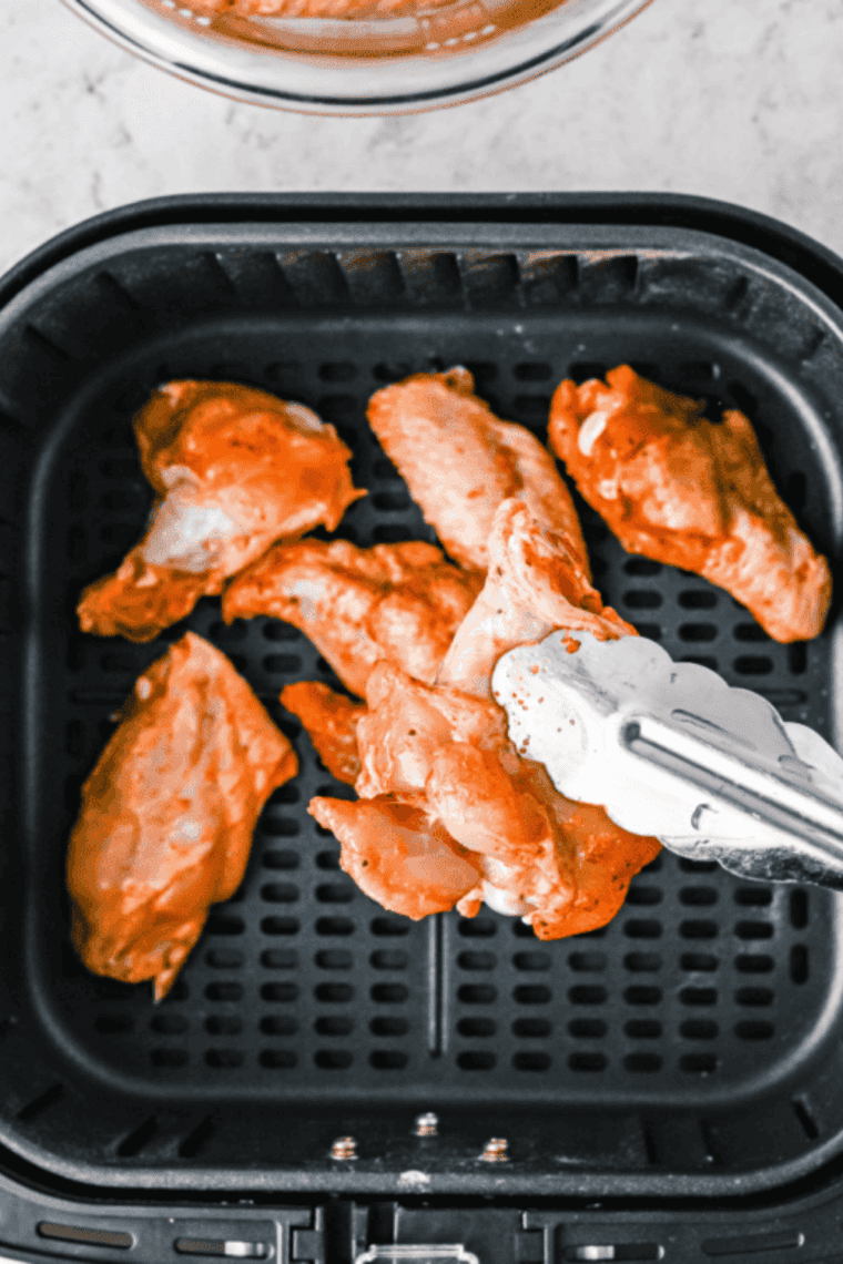 Wings cooking in an air fryer at 380&deg;F, flipping halfway for even crispiness