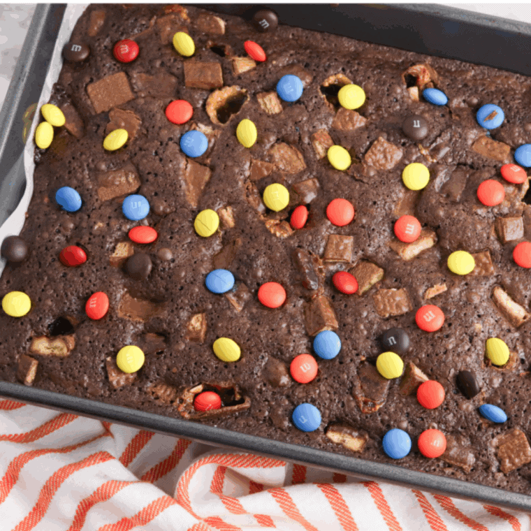 Fudgy brownies loaded with chopped leftover Halloween candy on a plate, ready to serve