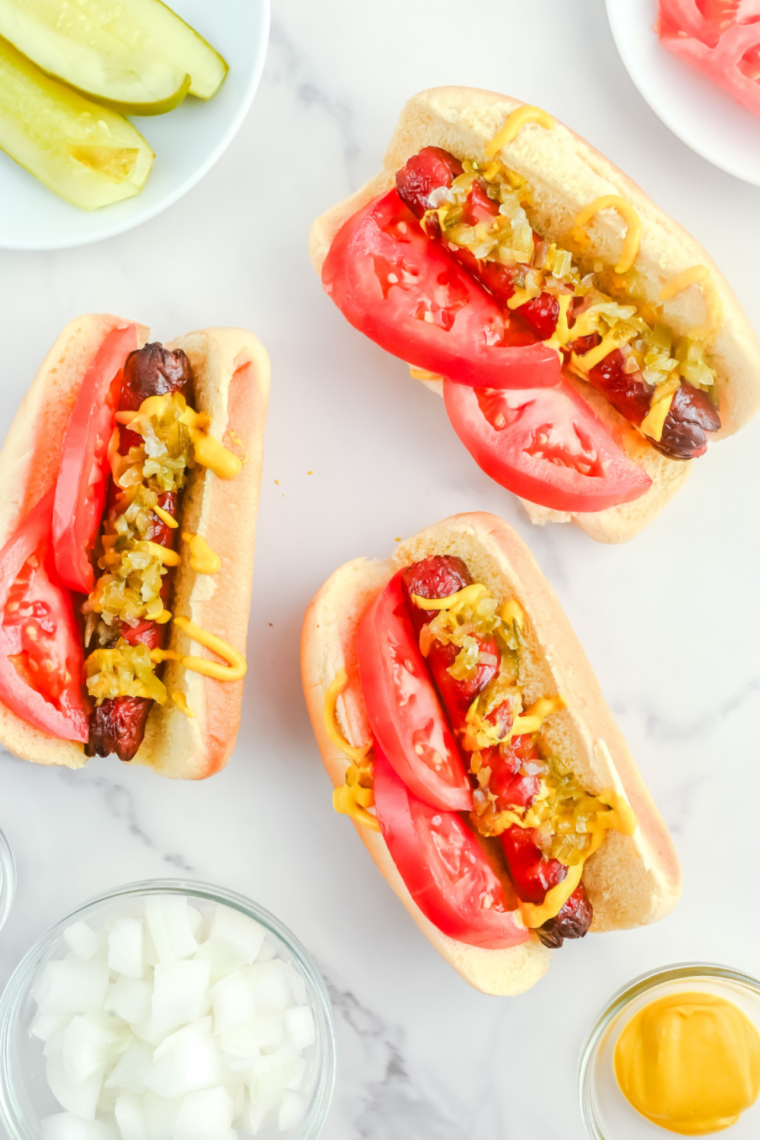 Air fryer Chicago hot dog served on a poppy seed bun with mustard, neon relish, chopped onion, tomato wedges, pickle spear, sport peppers, and celery salt.