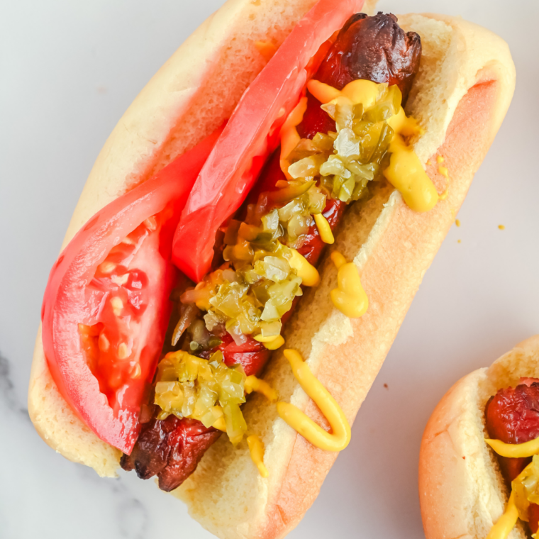 Chicago-style hot dog made in the air fryer on a poppy seed bun with mustard, relish, onions, tomato, pickle spear, sport peppers, and celery salt.
