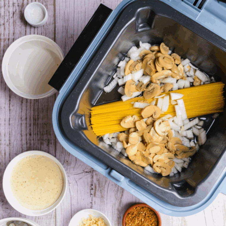Spaghetti, vegetables, Alfredo sauce, Cajun seasoning, and chicken cooking in the Ninja Speedi on Speedi Meals setting