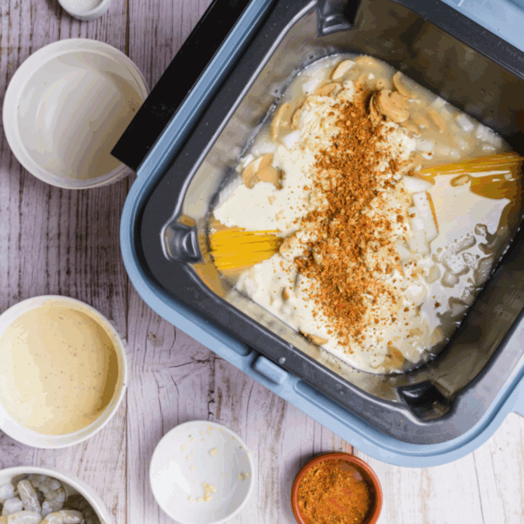 Mixing pasta and sauce ingredients, then placing diced chicken, smoked sausage, and shrimp on the Ninja Speedi crisper tray
