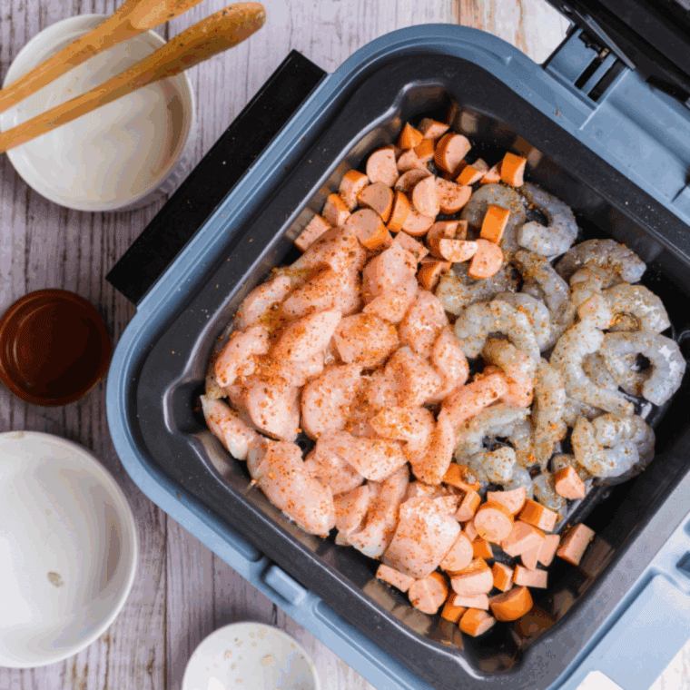 Adding cooked chicken, sausage, and shrimp to spaghetti mixture and stirring well before serving
