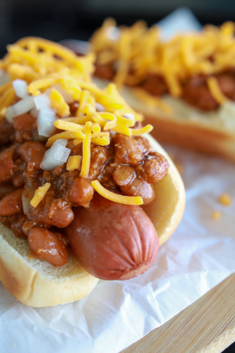 Frozen hot dogs cooking in an air fryer basket, turning hot and lightly crisp on the outside with juicy centers, ready to serve in buns.