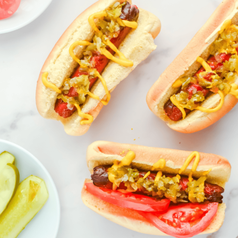 Frozen hot dogs cooking in an air fryer basket, turning golden and heated through with a lightly crisp exterior, ready for buns.