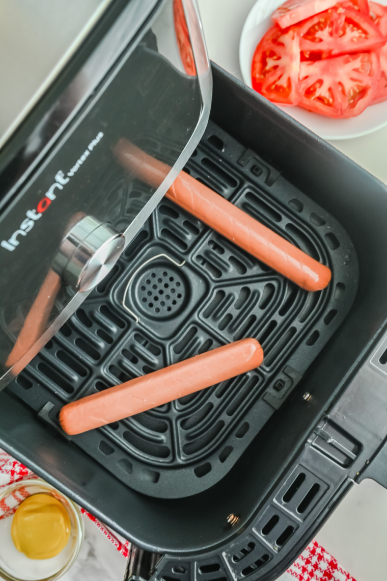 Frozen hot dogs being separated and prepared for air fryer cooking.