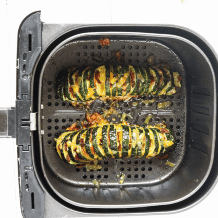 Golden Hasselback zucchini garnished with grated Parmesan and fresh herbs, ready to serve.