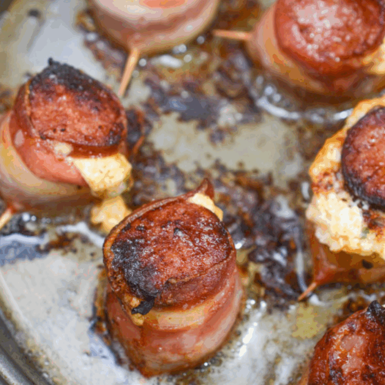 Pig shots arranged in a single layer in the air fryer basket, cooking until the bacon turns crispy and the filling bubbles.