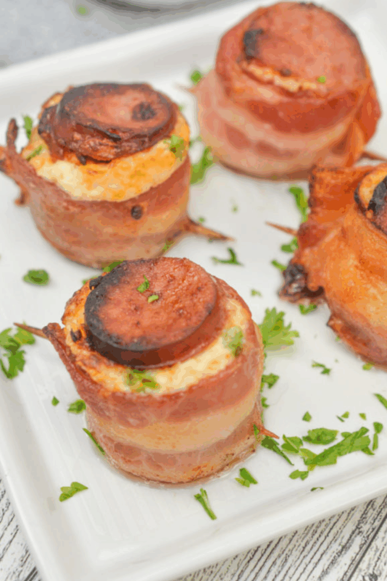 Air fryer pig shots made with crispy bacon, sausage slices, and creamy cheese filling on a platter.