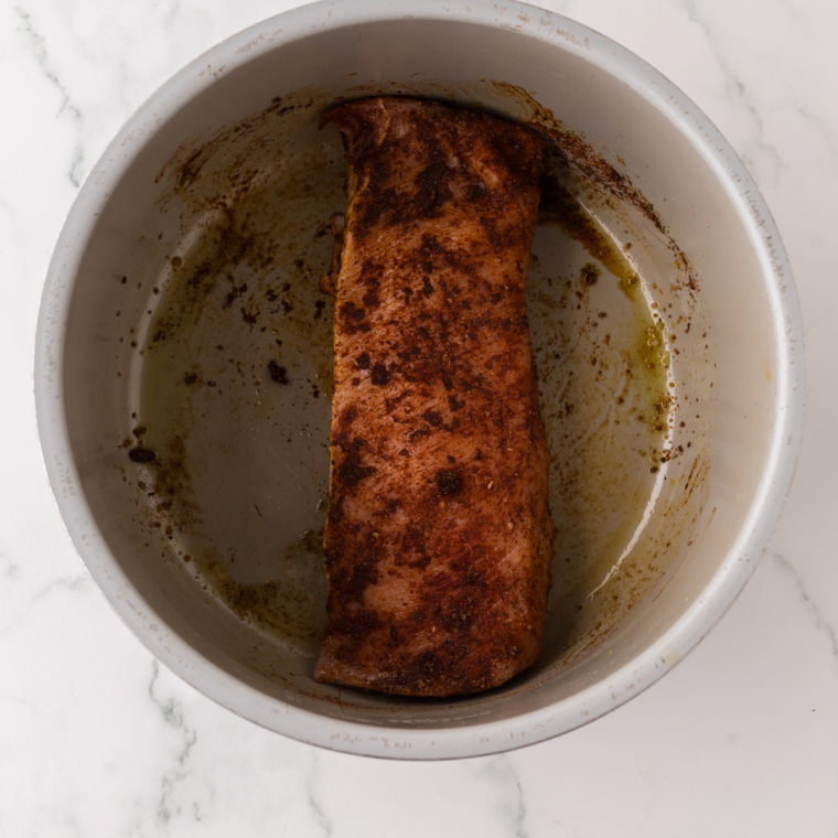 Pork tenderloin being patted dry and coated with olive oil and seasonings
