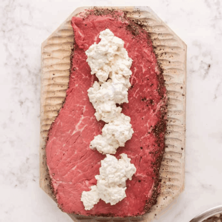 Flank steak seasoned and filled with blue cheese mixture, tightly rolled and tied with cooking twine