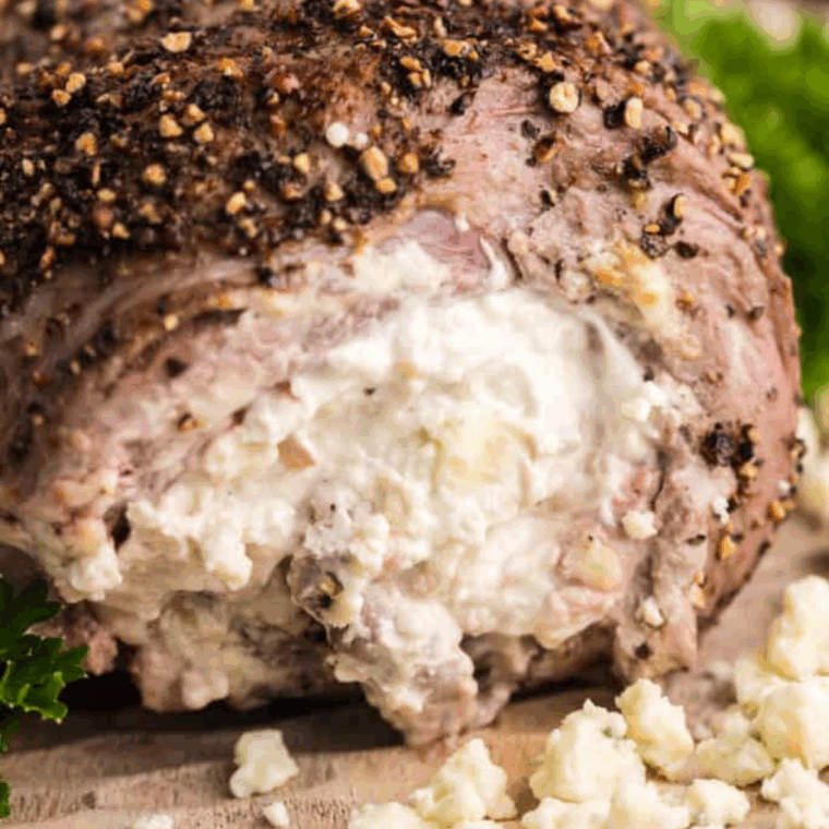 Sliced flank steak pinwheels cooked in the air fryer, revealing a creamy, blue cheese and spinach stuffing in the center.