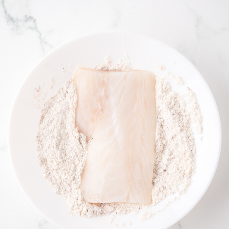Raw tilapia fillets patted dry and arranged in a parchment-lined baking dish