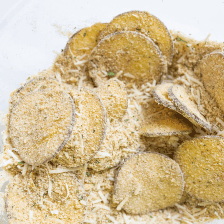 Eggplant slices being dredged in flour, egg, and breadcrumb-cheese mixture.