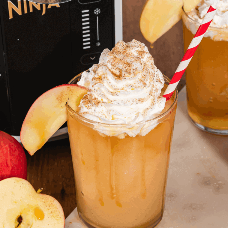 Easy Ninja Slushi Apple Cider Slush — frosty apple cider slush in a glass, topped with whipped cream and cinnamon.acked with crisp apple flavor!