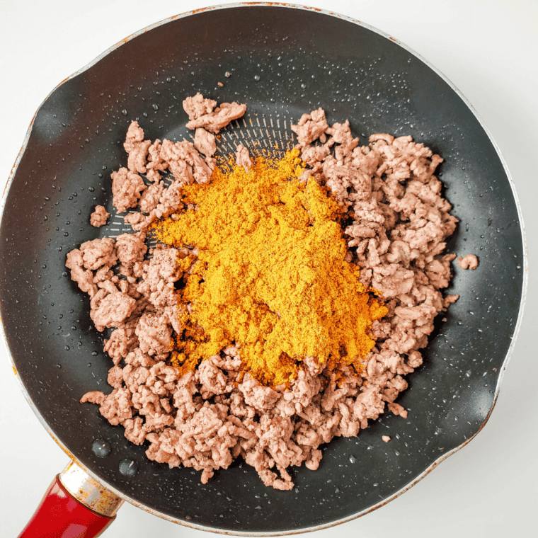 Ground beef browned with taco seasoning and refried beans in a skillet for taco pizza filling