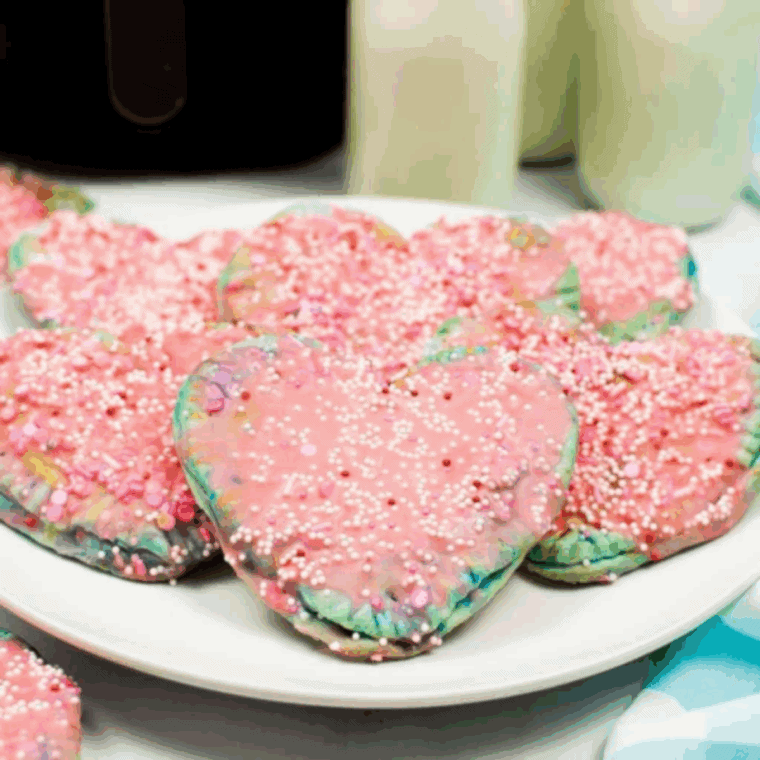 Golden heart-shaped Valentine’s Day pop-tarts with pink icing and sprinkles, freshly air-fried and ready to serve.