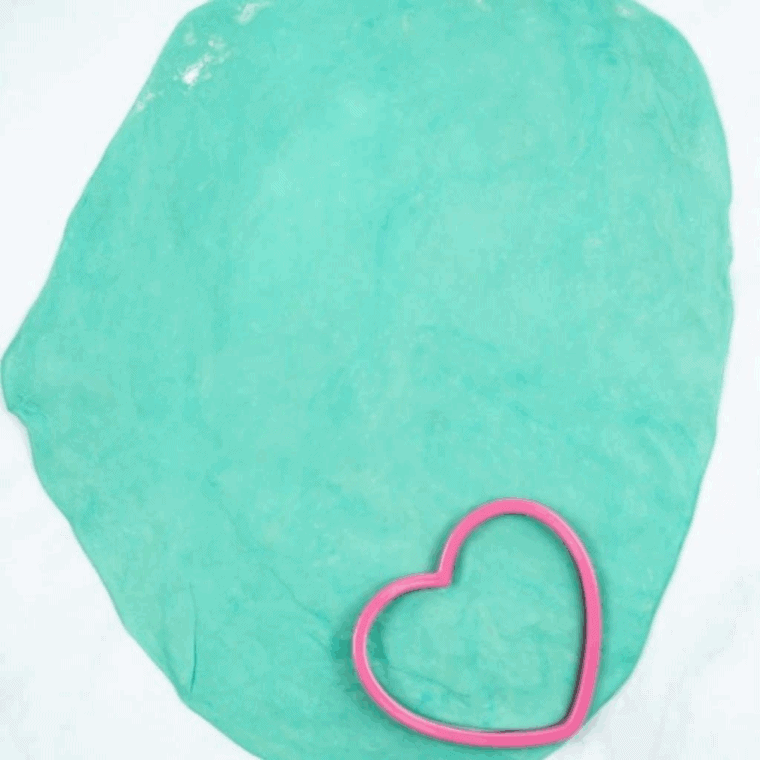 Rolling out pre-made pie crusts on a clean surface with a rolling pin to flatten for heart-shaped Valentine’s Day pop-tarts.