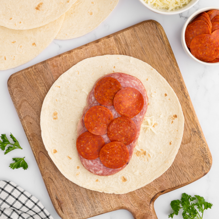 Flour tortilla with layers of Italian deli meats, provolone, mozzarella, and optional veggies sprinkled with Italian seasoning.