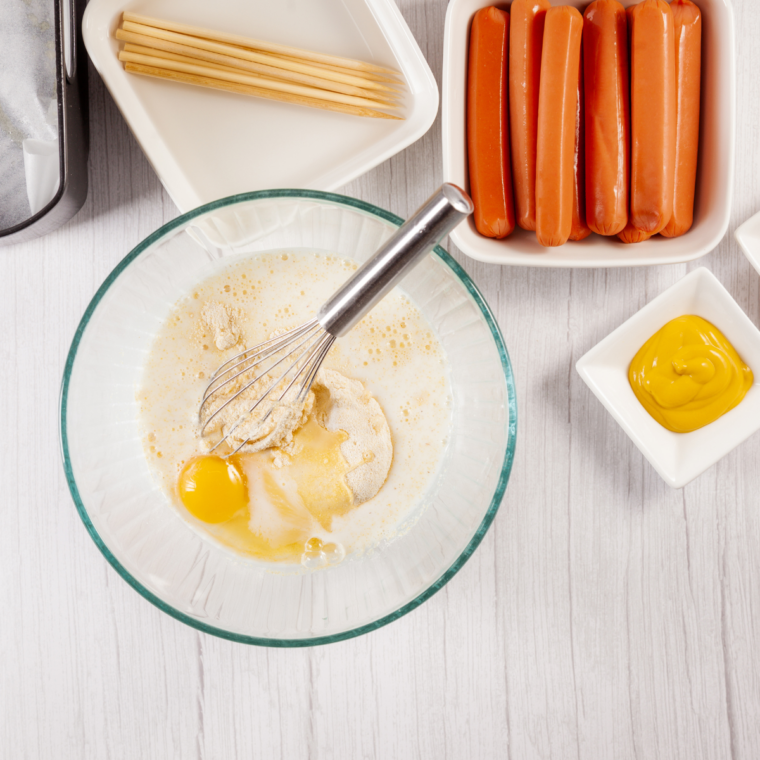 Whisking cornbread mix, milk, egg, and sugar until smooth batter forms.