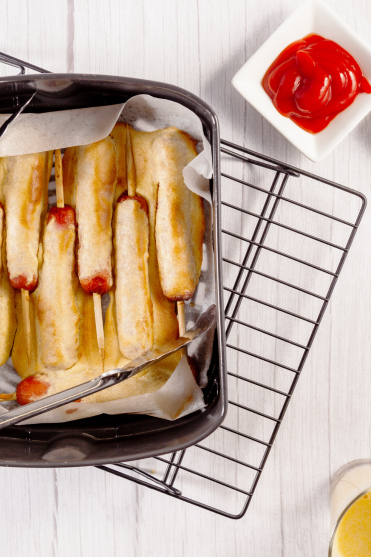 Air fryer corn dogs with golden cornbread coating, served hot on a plate with ketchup.