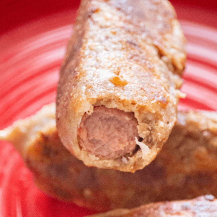 Golden keto corn dogs cooked in the air fryer, served hot on a plate with wooden skewers.