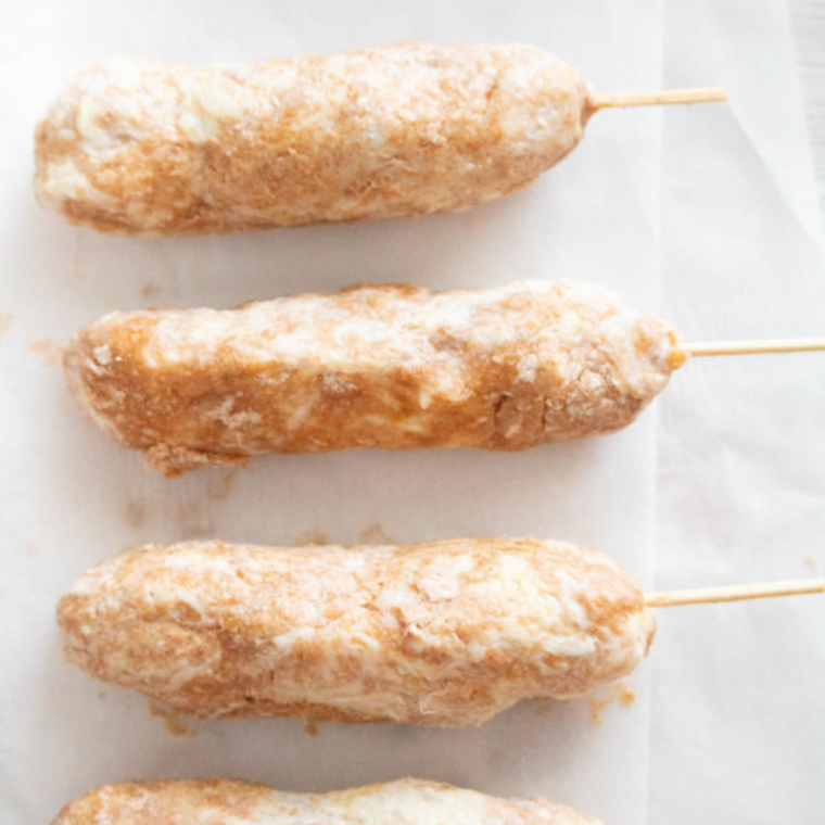 Hot dogs wrapped in dough placed in the air fryer basket, ready to cook.