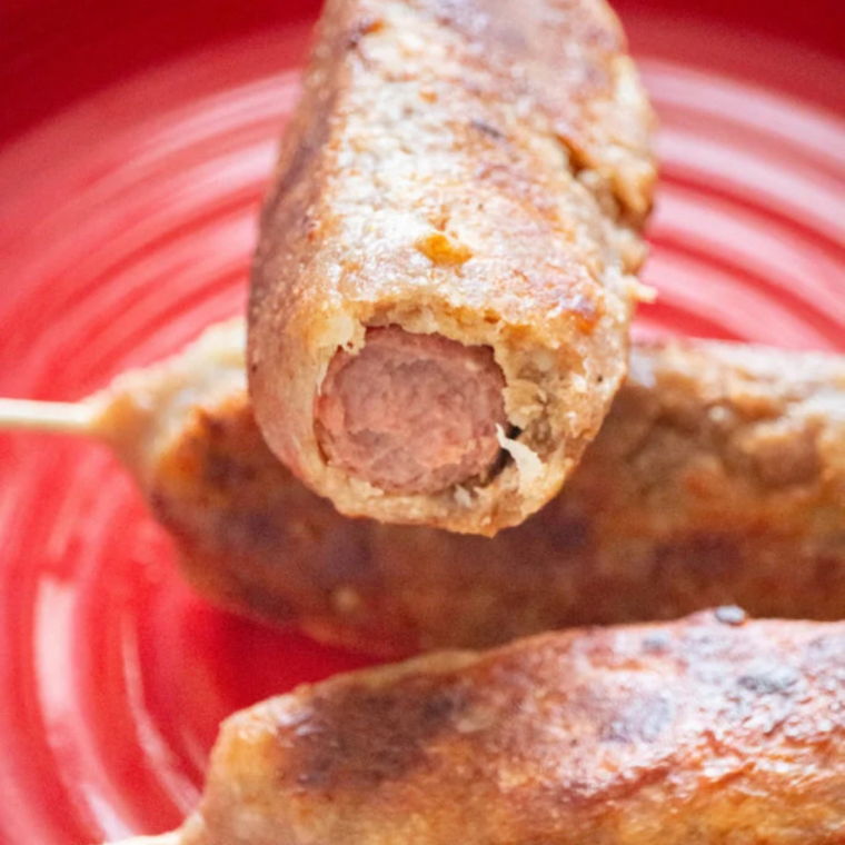 Golden air fryer corn dogs resting on a plate before serving.