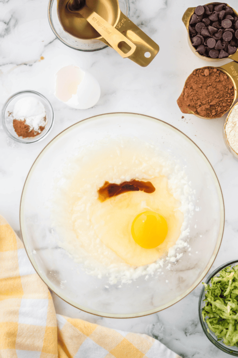 Grated zucchini being squeezed with a clean towel to remove excess moisture.