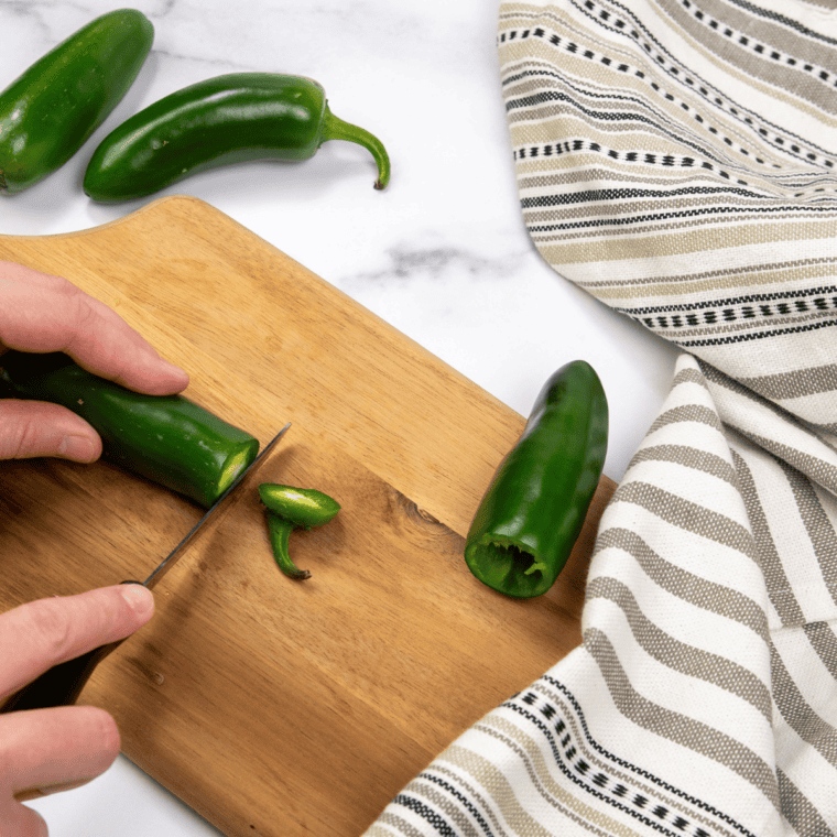 Fresh jalape&ntilde;o peppers being boiled in a pot after removing stems and seeds.