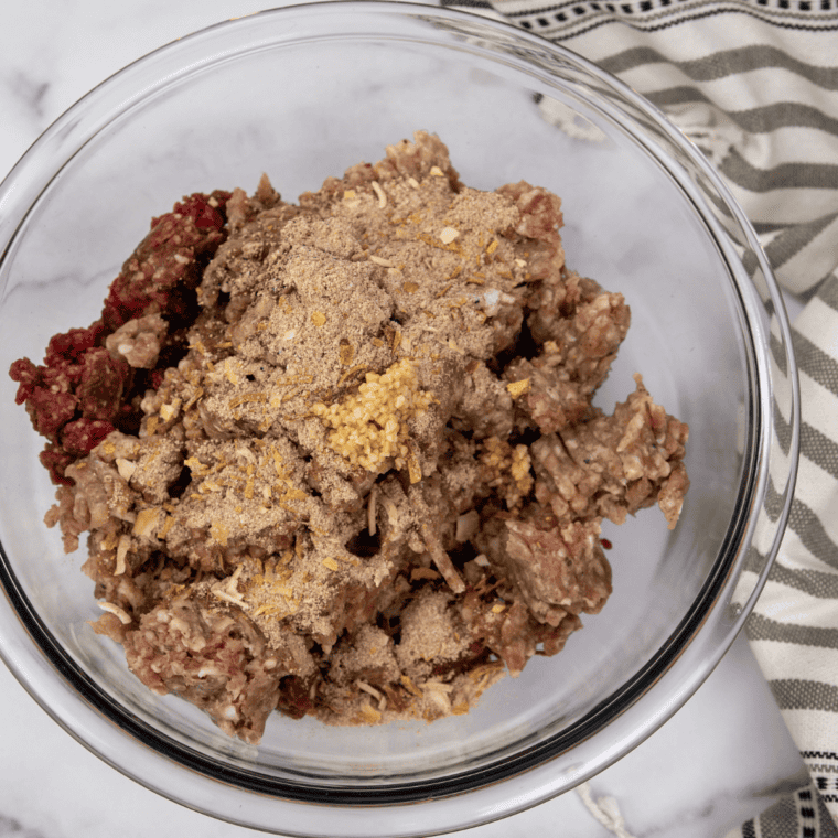 Air Fryer cooking bacon-wrapped armadillo eggs, flipping halfway through for even crisping.