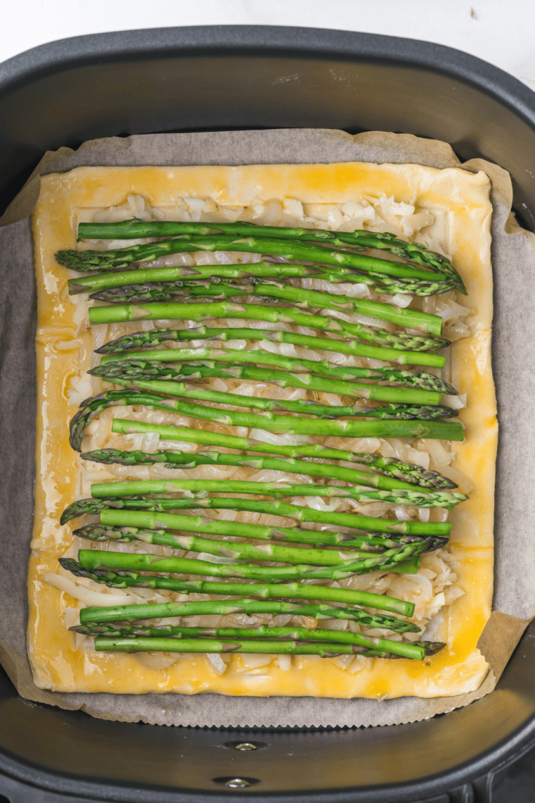 Air fryer asparagus tart sliced and garnished with herbs, nuts, and orange zest.