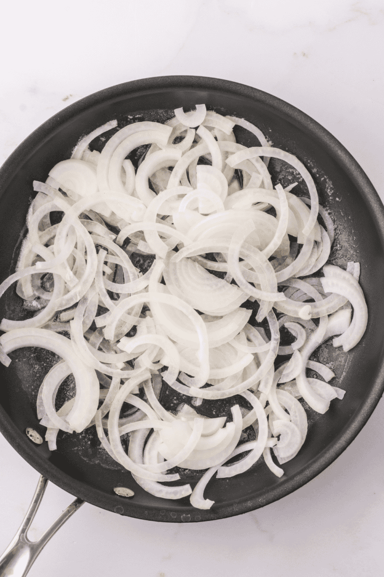 Saut&eacute;ed onions cooking in butter in a small skillet.