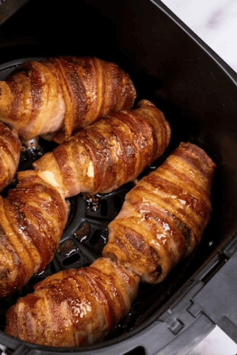 Golden-brown Air Fryer Armadillo Eggs with melted cheese inside, served on a plate with toothpicks.
