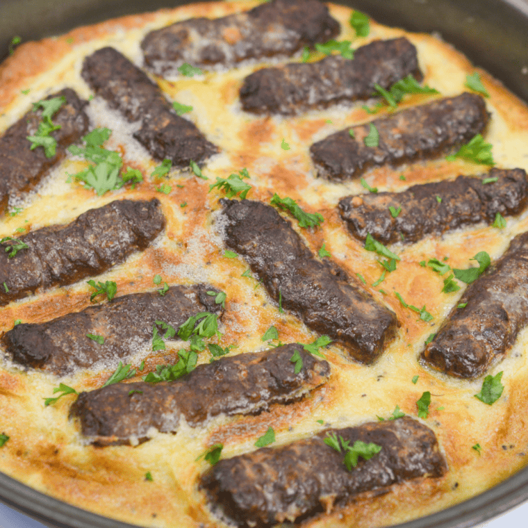 Golden air fryer toad in the hole with crispy puffed batter and four browned pork sausages in a small metal dish