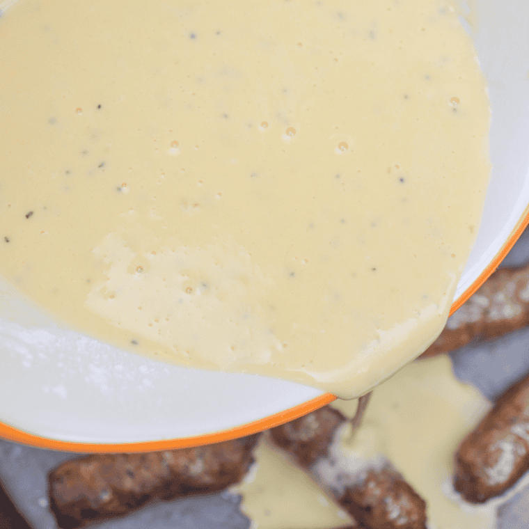 Whisking flour, eggs, milk, and seasoning together in a glass bowl until smooth for toad in the hole batter