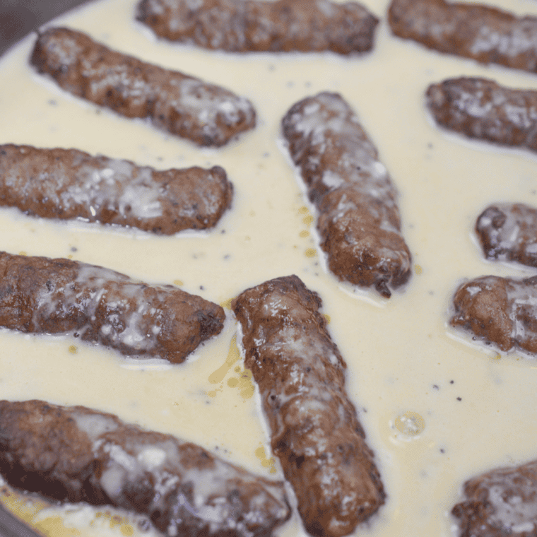 Yorkshire pudding batter being poured around sizzling sausages in a hot air fryer dish