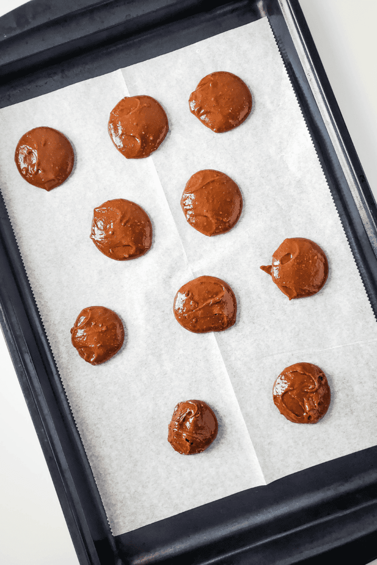 Scoop the dough: "Mounds of brownie cookie dough scooped onto a parchment-lined baking sheet, spaced apart