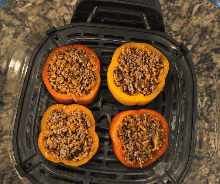Pepper halves packed with beef and rice filling, mounded slightly, in the air fryer container