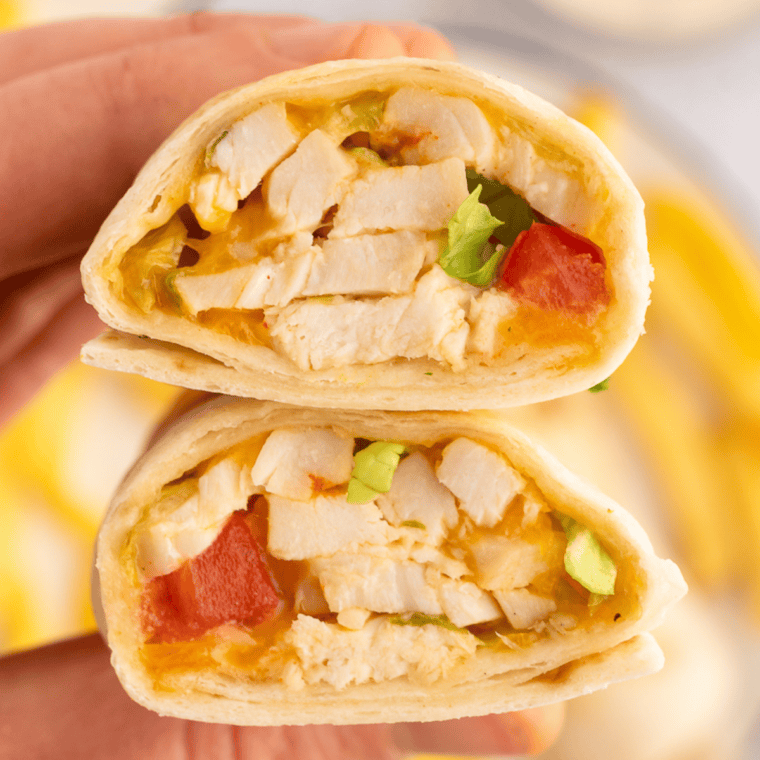 Air fryer chicken snack wrap cut in half showing shredded chicken, melted cheddar, and ranch inside a crispy golden tortilla