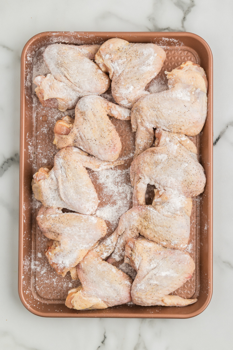 Chicken wings tossed with baking powder and smoked paprika rub in a mixing bowl
