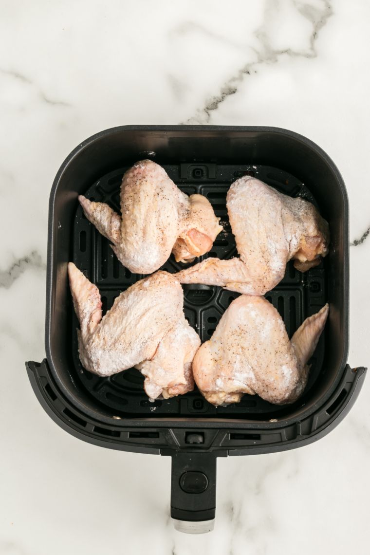 Seasoned chicken wings in a single layer in the air fryer basket